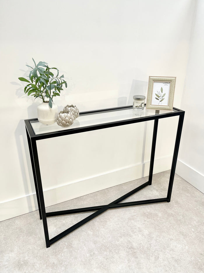 cross legged console table with black metal legs and glass top
