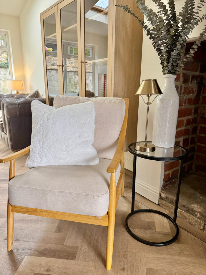 Cozy living room with a beige armchair, side table, and decorative elements.